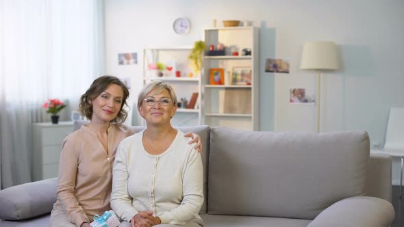 Mature Mother and Daughter Looking at Small Child Giving Tulips, Smiling Camera