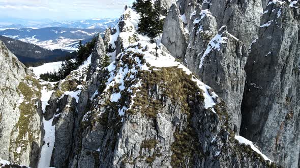 Aerial drone view of the spring Carpathians, Romania. Rocky peak with cross, snow forest