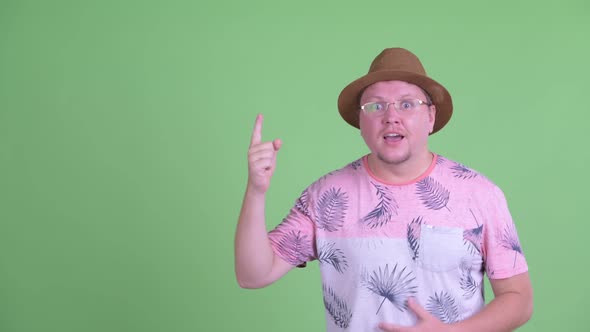 Happy Overweight Bearded Tourist Man Pointing Up and Looking Excited