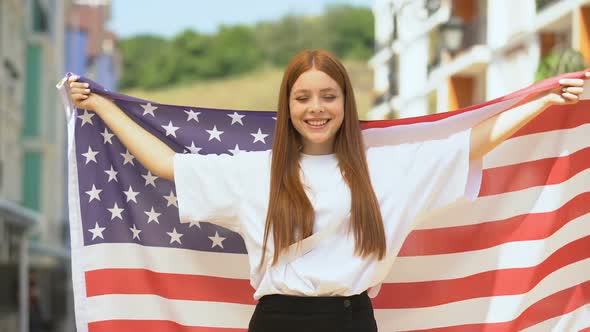 Cheerful Female Teen Waving Flag of USA and Sending Air Kiss on Camera, Patriot