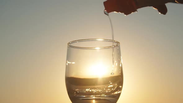 Filling Glass with Water at the Sunset Slow Motion