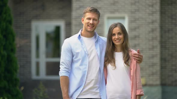 Smiling Couple Showing Thumbs Up, Standing Against House, Real Estate Purchase