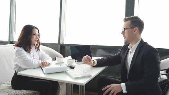 Confident Man and Woman in Formal Wear Sit Talking Discussing in Restaurant