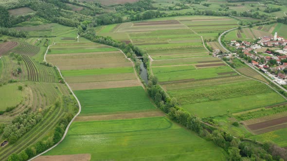 High drone shot of river and agriculture fields, roads, vine trees and small village on the side. Be