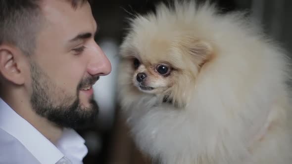 Bearded Man in White Shirt Holds His White Fluffy Spitz in Hands and Tries To Rub His Nose with Him