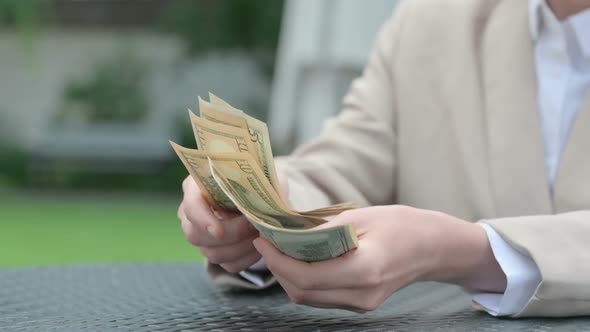 Businesswoman Feeling Sad While Counting Dollars in Outdoor Cafe