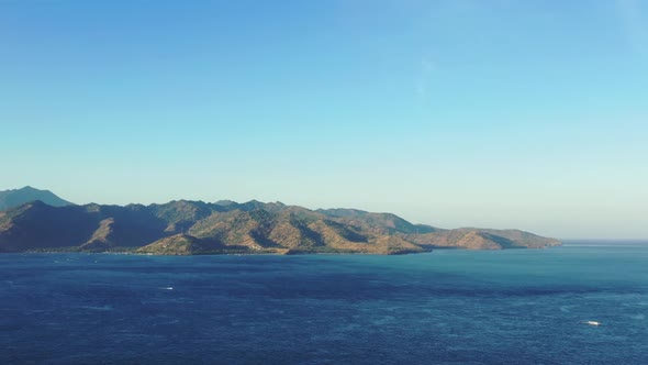 Aerial drone panorama of tranquil resort beach holiday by turquoise lagoon with bright sand backgrou