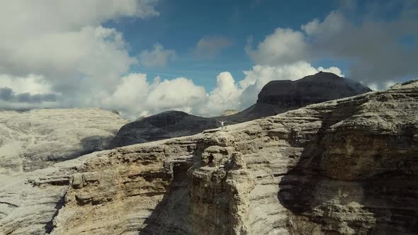 Zoom in Drone Shot of Hands Raised Woman Standing on the Top of Piz Boe Mountain