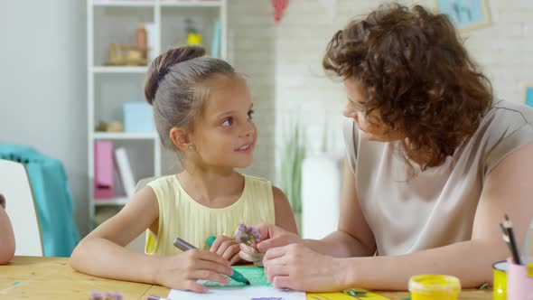 Female Teacher and Little Girl Drawing Together on Art Lesson alt