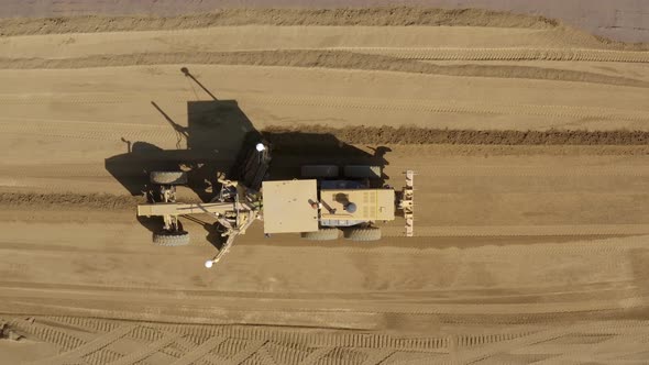 Top down Aerial view of a road grader pushing and leveling dirt on a construction site