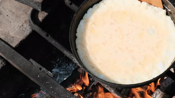 Cooking an Omelet on a Campfire in a Tourist Frying Pan in Nature