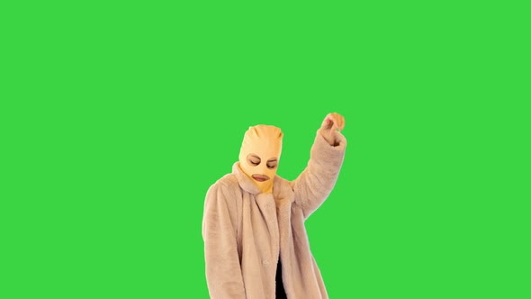 Young Daring Girl in Coat and Balaclava Dancing on a Green Screen Chroma Key