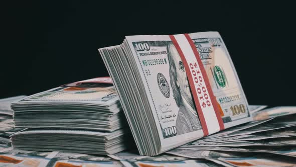 Bundles of Dollars Lying on a Pile of Money and Rotate on Black Background