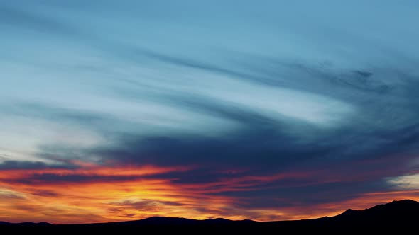 Sunrise timelapse in Mojave Desert with waves of vibrant color in clouds