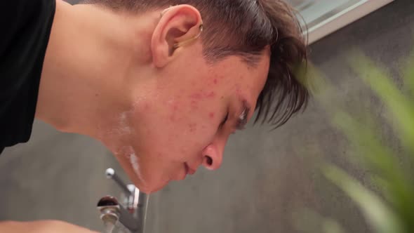 Handsome Young Man in Hearing Aids Washes Foam Off His Face in a Skincare Bathroom