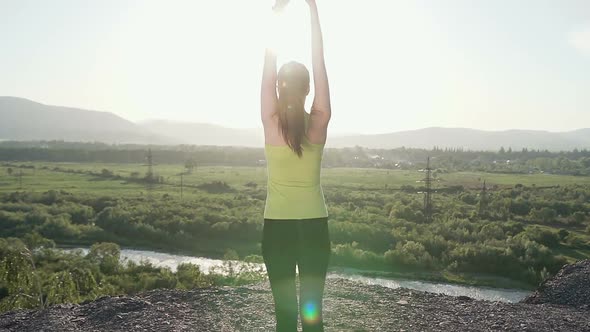 Young Sporty Woman Practicing Yoga on the Top of Mountain at Sunset