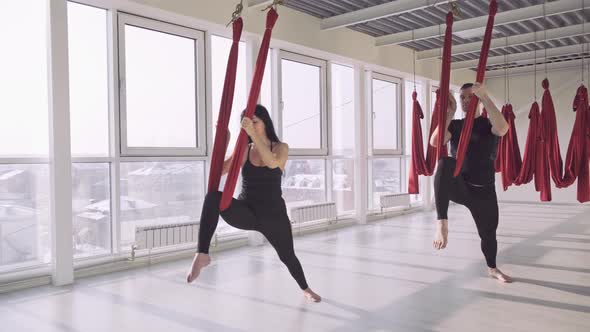 Man and a Woman Practice Aerial Yoga in Hammocks. Modern, Light Class.