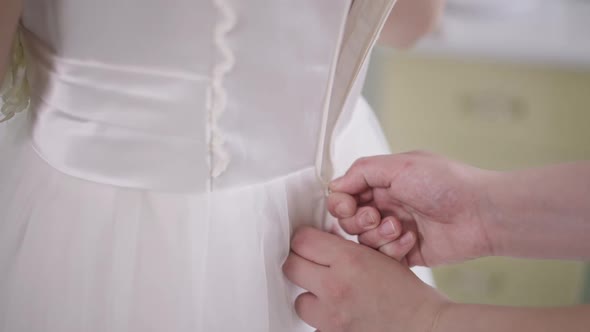 Closeup Zipping White Wedding Dress on Slim Caucasian Young Woman