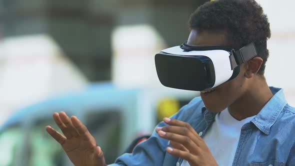 Excited African-American teen boy using VR headset, modern technology