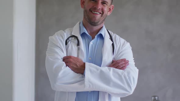 Portrait of caucasian male doctor smiling with arms crossed