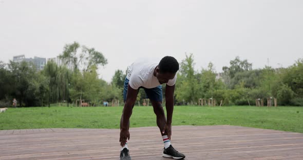 African American Man Warming Up with Exercises Before Intense Workout Outdoors