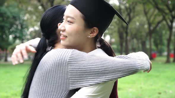 Young Asian Female Graduate Hugging Her Friend at Graduation Ceremony in Slow Motion