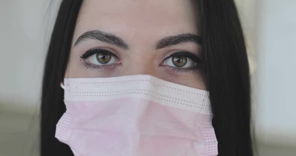 Close Portrait of Nurse in Medical Mask Looking Into Camera on Background