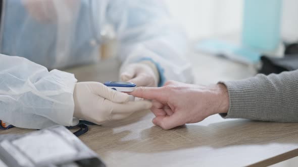 Unrecognizable Doctor or Nurse in Gloves Measuring Oxygen Saturation and Pulse Rate of Patient with