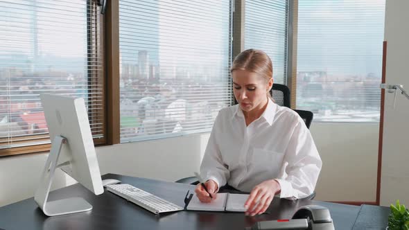 Woman Manager Reads Documents and Financial Reports Sitting at the Workplace and Typing Text on the