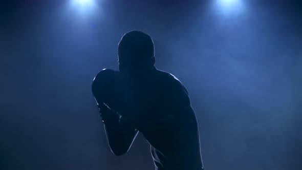 Sportsman Boxing in Smoky Studio. Silhouette on a Dark Background