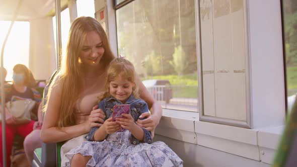 Woman and Daughter Using Mobile Phone Internet Social Network Application Traveling By Bus or Tram