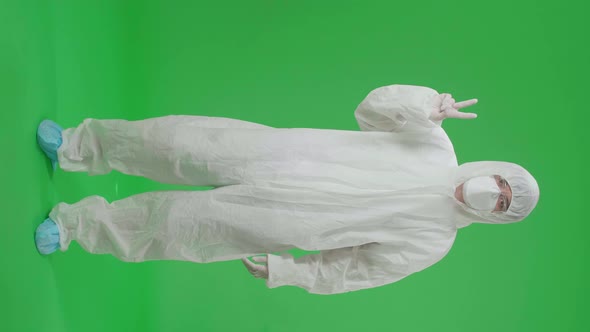 Male Wear Protective Uniform PPE And Smiling With A Victory Hand Sign In Green Screen Studio