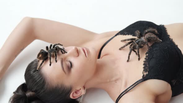 Close Up View Sexy Girl with a Big Black Spider Lies on a White Background