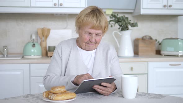 Smiling Senior Woman Using Tablet Computer Relaxing At Home