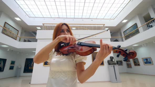Violin Is Getting Played By a Female Musician in a White Dress