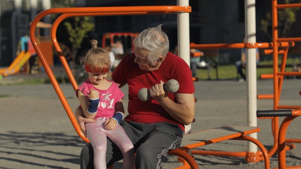 Granddaughter and Grandfather Doing Fitness Exercises with Dumbbells. Senior Man with Child Kid Girl