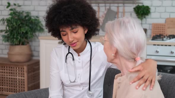 Afro American Woman Doctor Wishes Well for a Senior Woman Putting Her Hand on Her Shoulder