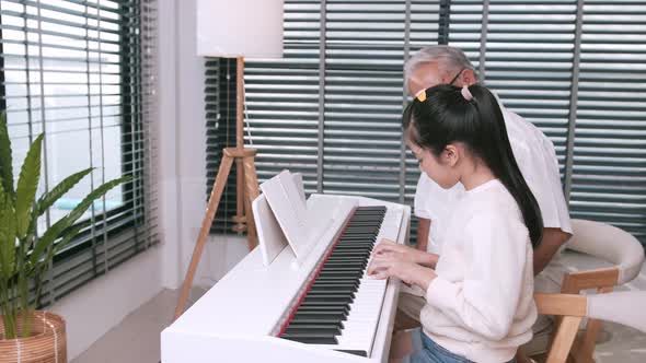 The family's grandfather was happy to listen to her granddaughter play the piano and clapped her han