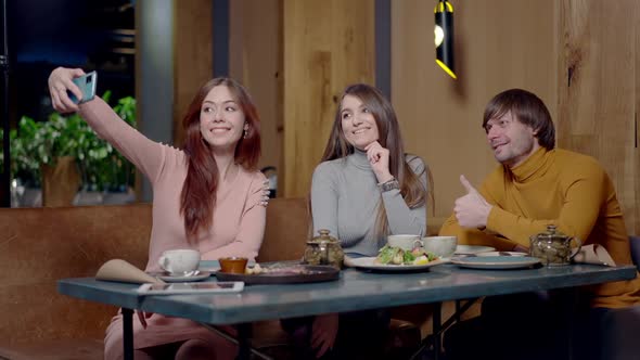 Positive Relaxed Caucasian Friends Taking Selfie Sitting at Table in Restaurant