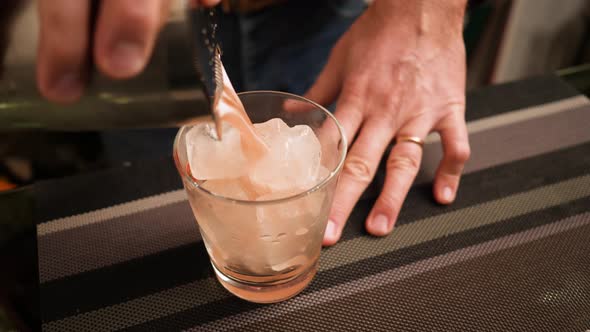 Bartender bartender pouring cocktails using a colander to make a cocktail.