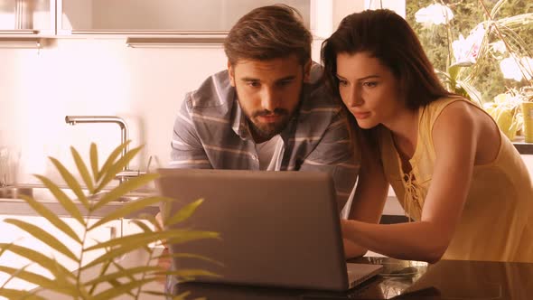 Couple using laptop in the kitchen