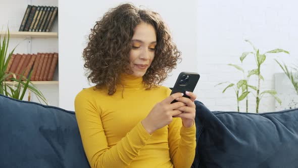 Happy Millennial Teen Girl Checking Social Media Holding Smartphone at Home