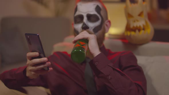 Man Drinking Beer and Using Mobile Phone on Halloween