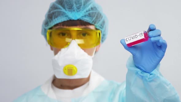 Doctor in Biohazard Ptotective Suit Holding Sample of Coronavirus in Test Tube