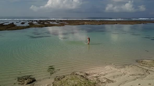 Woman in a Bikini Playing with Water on the Beach