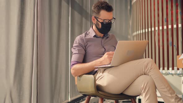 Businessman In Face Mask Working On Laptop In Office.Businessman In Face Mask On Coronavirus