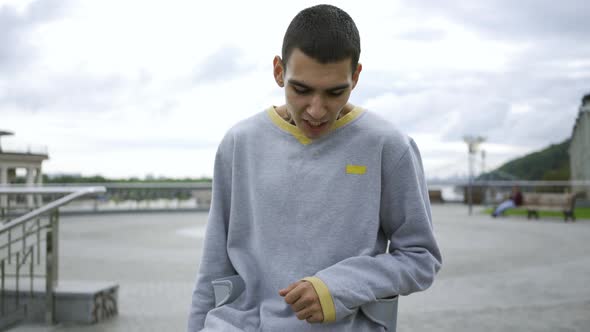 Portrait of a Young Sports Man with a Tattoo on His Neck Standing Against the Sky with Clouds