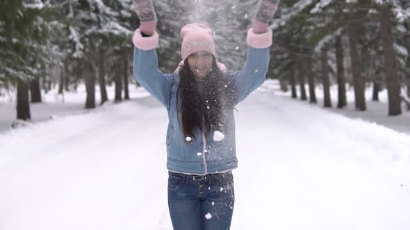 A Girl in a Good Mood Throws Snow Over Her Head Standing in the Winter Forest and Smiling