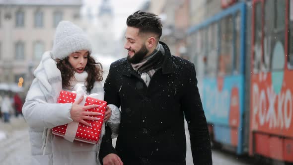 A Man and a Woman are Walking Through the City Center in a Snowfall