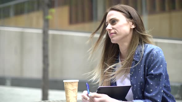 Thoughtful woman writing in a diary